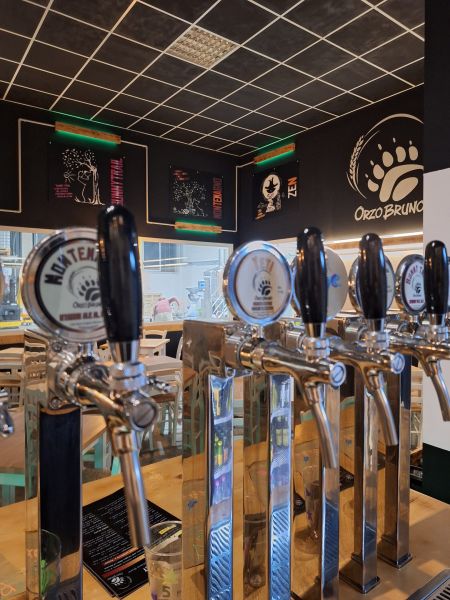 Spine per la mescita delle birre artigianali OrzoBruno all’interno del locale, con il logo del birrificio e le grafiche delle diverse birre sulle pareti.