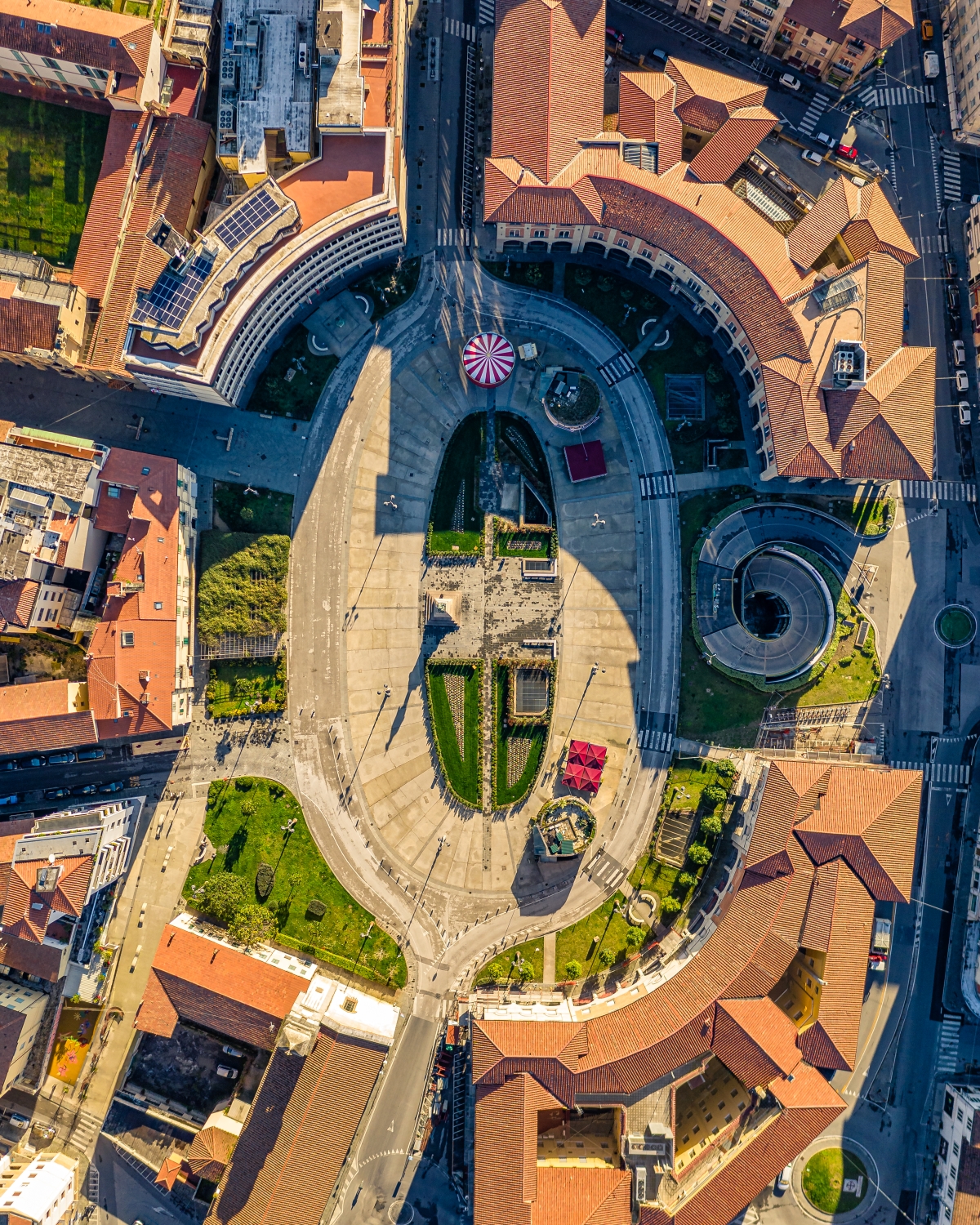 Veduta aerea di Piazza Vittorio Emanuele II a Pisa, con la grande area pedonale centrale, i giardini geometrici e gli edifici storici che circondano la piazza.
