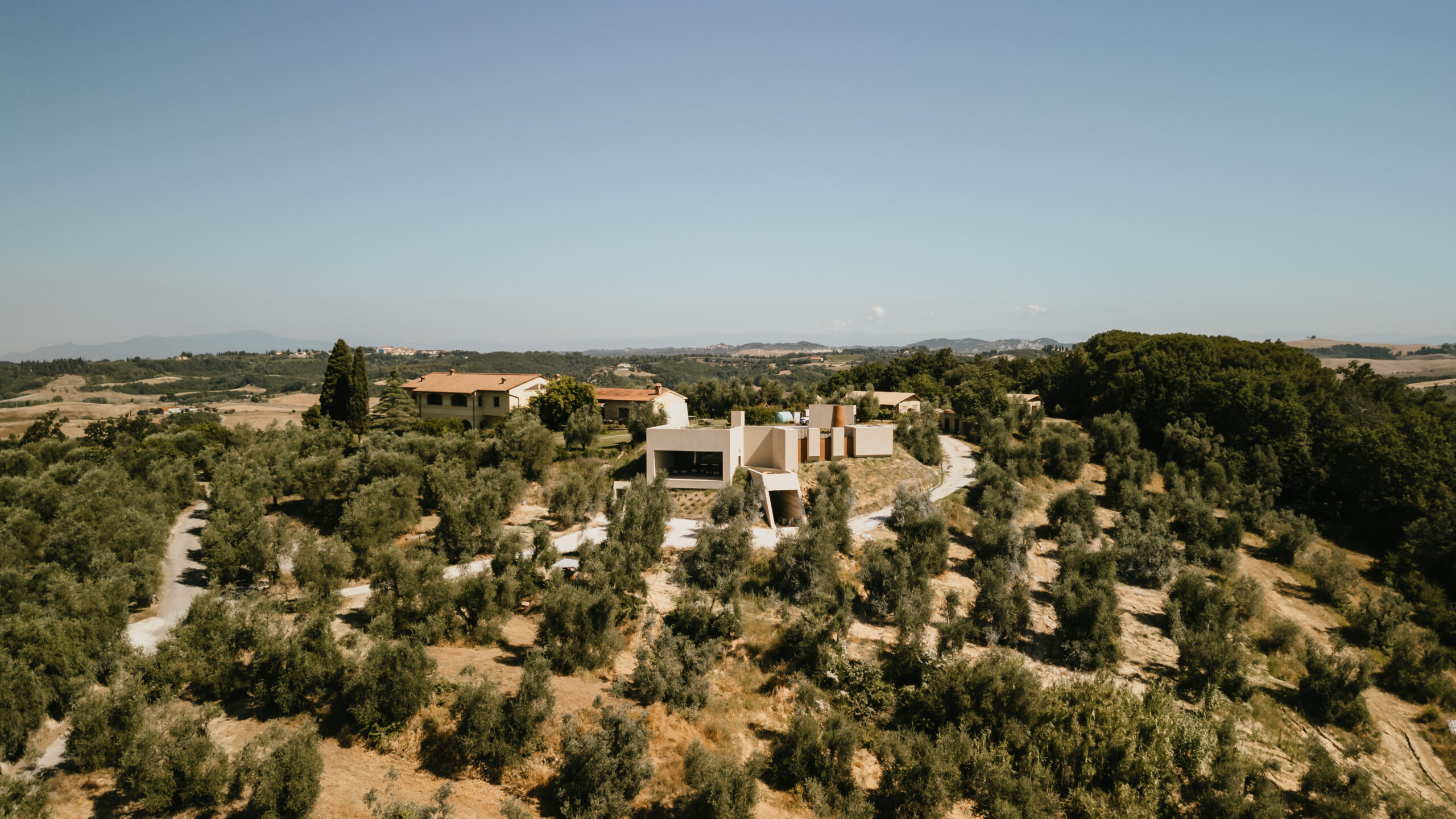 Veduta aerea dell’Antica Fornace tra le colline della Valdera, con oliveti, boschi e gli edifici dell’azienda immersi nel paesaggio rurale di Peccioli.