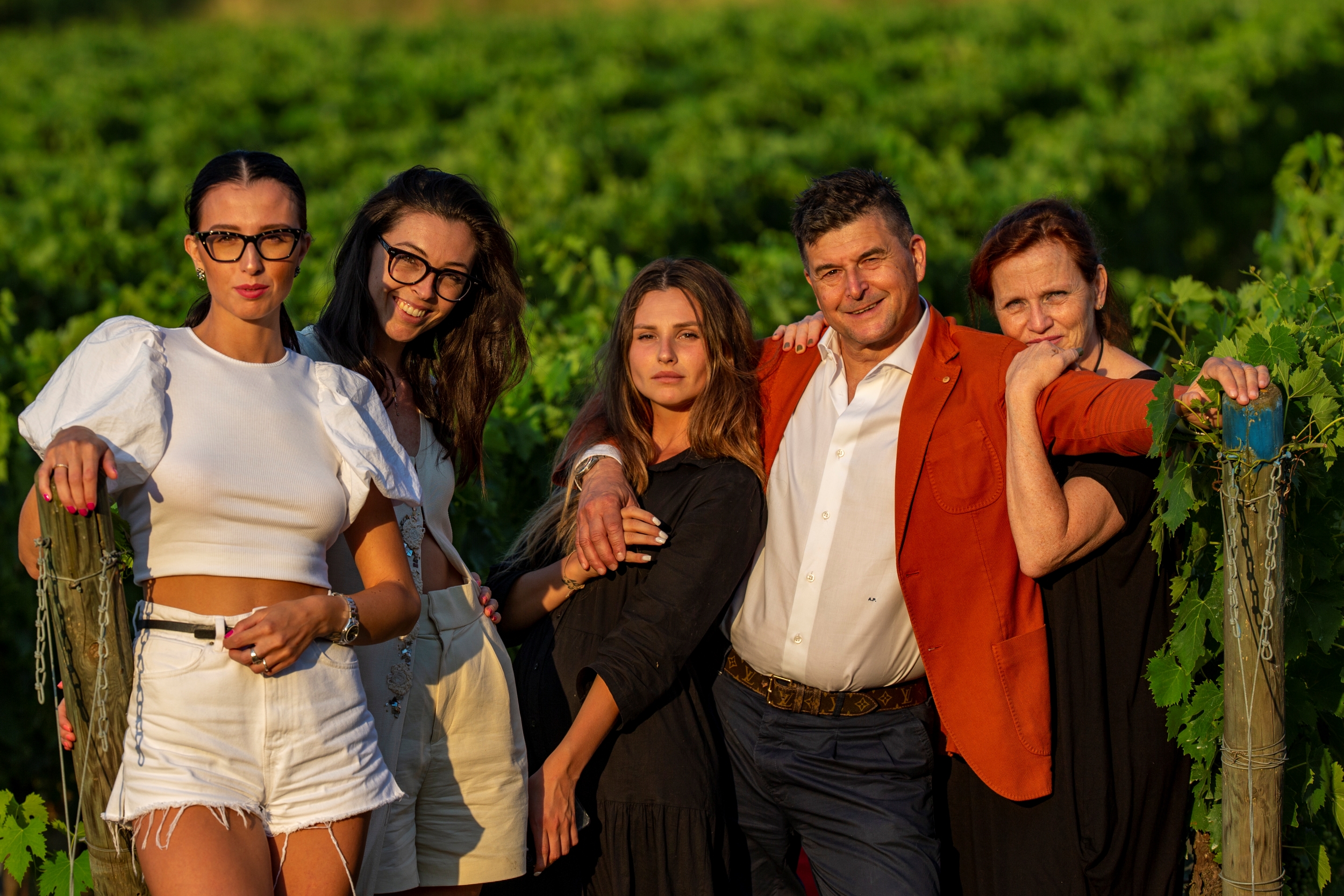 La famiglia dell’azienda vinicola L’Agona posa tra i filari della tenuta di Terricciola, illuminata dalla luce calda del tramonto.