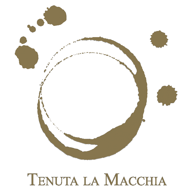 Una donna posa sorridente tra i filari della Tenuta La Macchia, affacciata all’interno di una cornice con il nome dell’azienda e la scritta “I più piccoli viticoltori della Costa Toscana”. Sullo sfondo si vedono il vigneto, la vegetazione e il cielo azzurro.