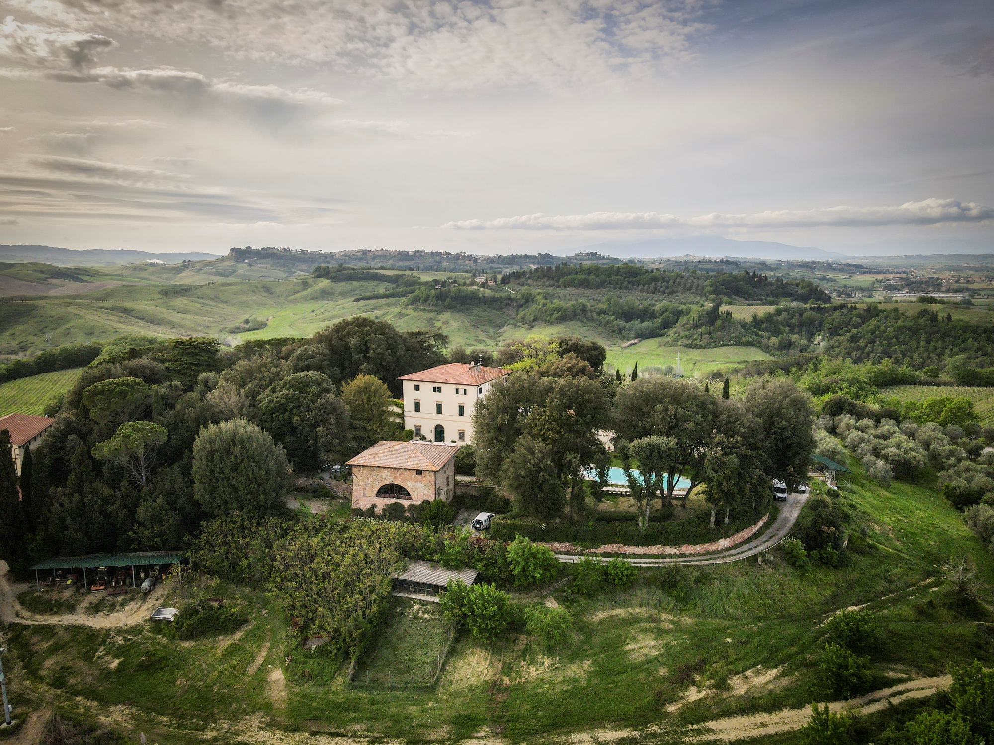 Veduta aerea di Pieve de’ Pitti, con la villa storica e gli edifici rurali immersi nel verde, circondati dalle colline, dai vigneti e dagli oliveti di Terricciola.