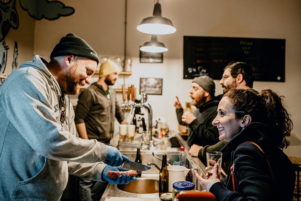Tap Room del Birrificio La Staffetta di Calci con birraio al bancone e clienti durante una degustazione.