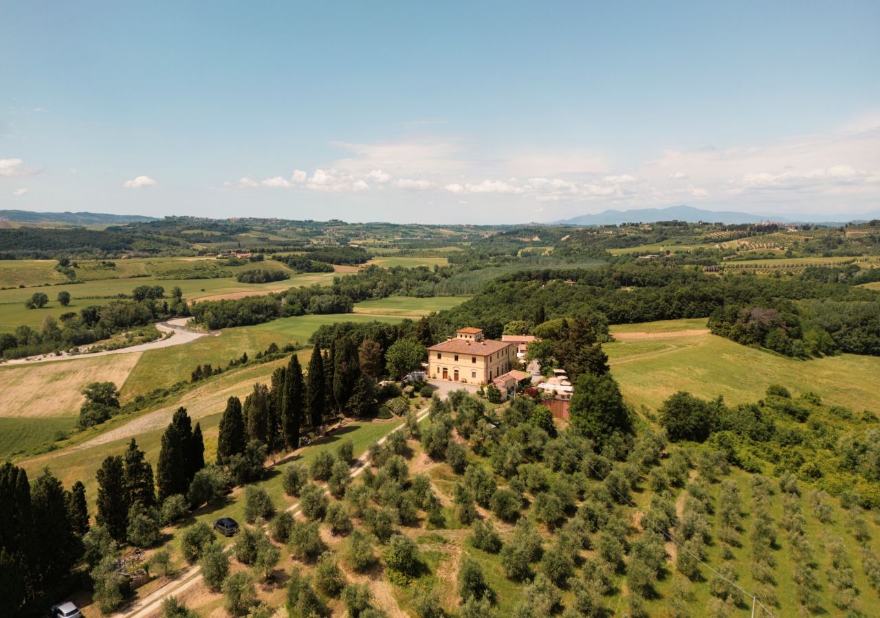 Veduta aerea dell’Azienda Agricola I Moricci, con la villa circondata da oliveti, cipressi e verdi colline nel paesaggio rurale di Peccioli.
