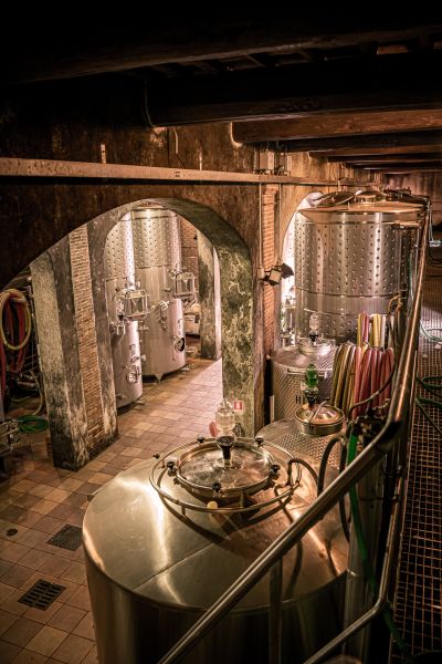Interno della cantina di Varramista, con grandi serbatoi in acciaio inox disposti negli ambienti storici ad archi e travi in legno.