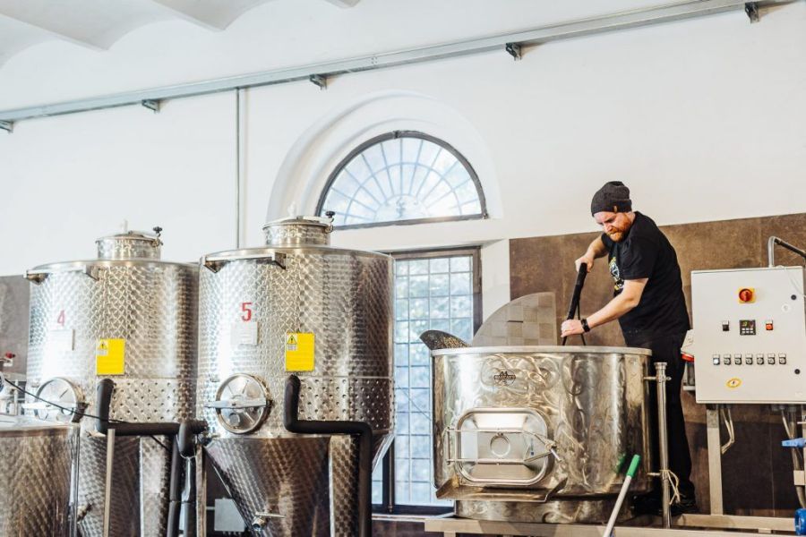 Birraio del Birrificio La Staffetta al lavoro sull’impianto di produzione, accanto ai fermentatori in acciaio.