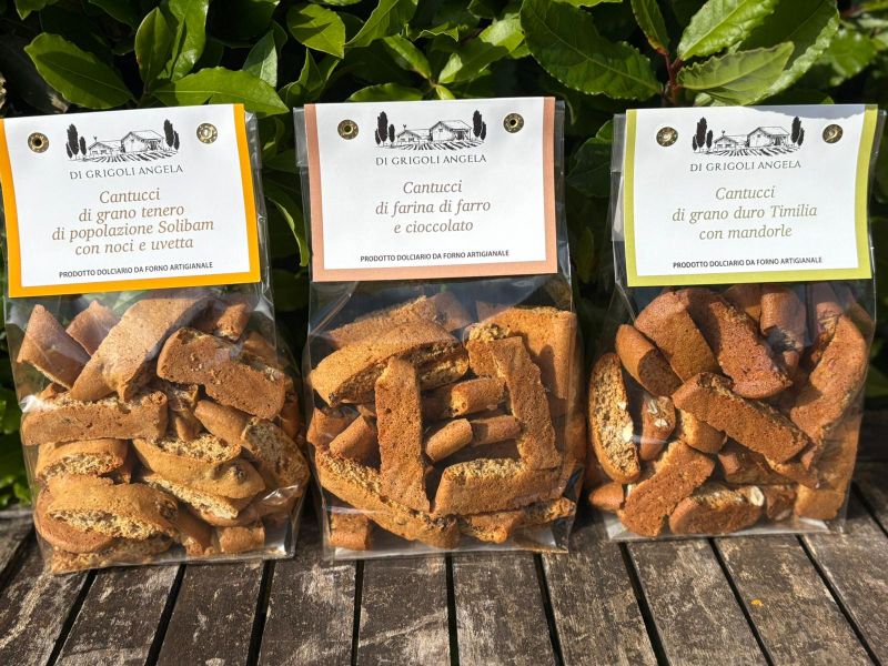 Tre confezioni di cantucci artigianali dell’Azienda Agricola Di Grigoli Angela, preparati con grano tenero Solibam, farro e cioccolato, e grano duro Timilia con mandorle.
