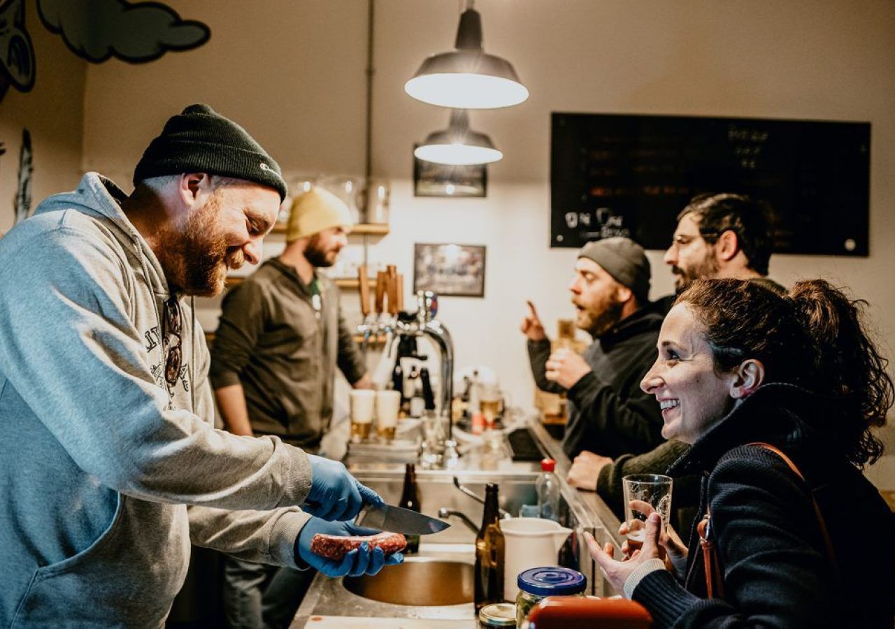 Tap Room del Birrificio La Staffetta di Calci con birraio al bancone e clienti durante una degustazione.