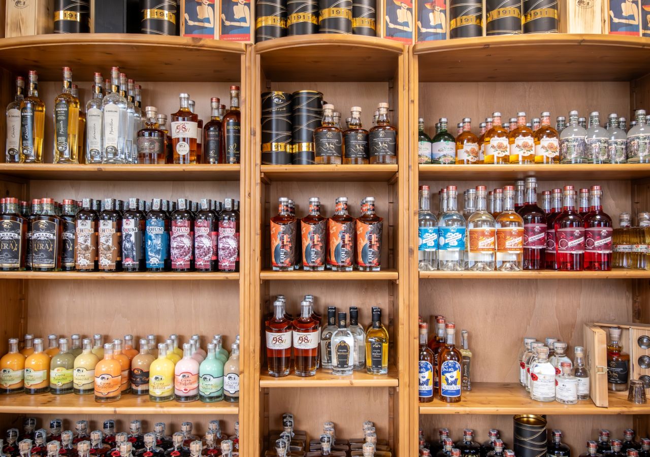 Scaffali in legno con un’ampia selezione di liquori e distillati Liquori Morelli, disposti in bottiglie di diversi formati, colori ed etichette