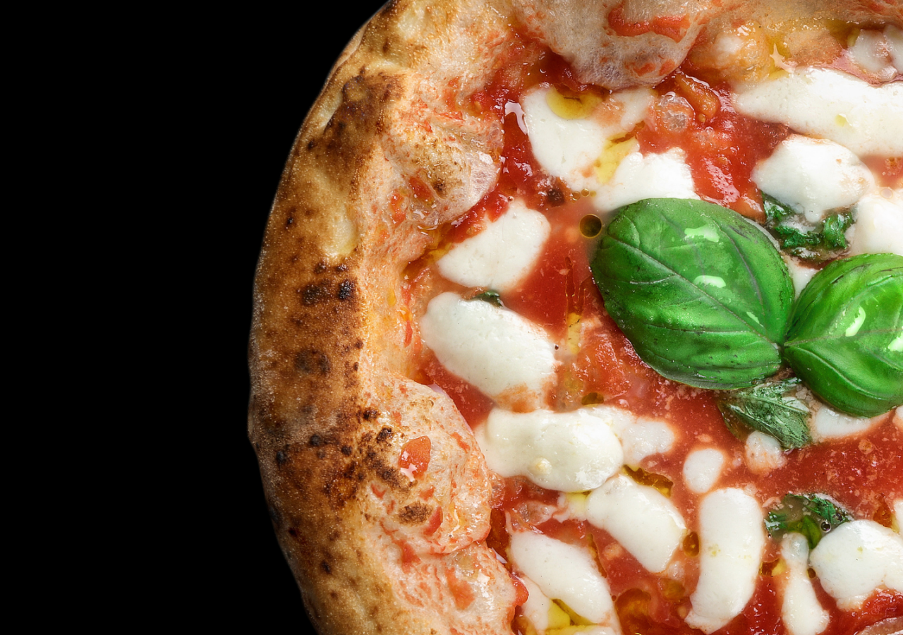 Primo piano di una pizza margherita contemporanea con pomodoro, mozzarella, basilico fresco e cornicione alto e ben cotto, su sfondo nero.